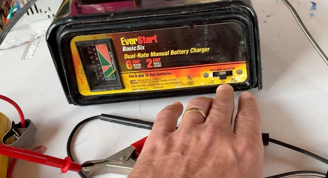 Checking battery health with a multimeter before using a dual-rate EverStart charger.